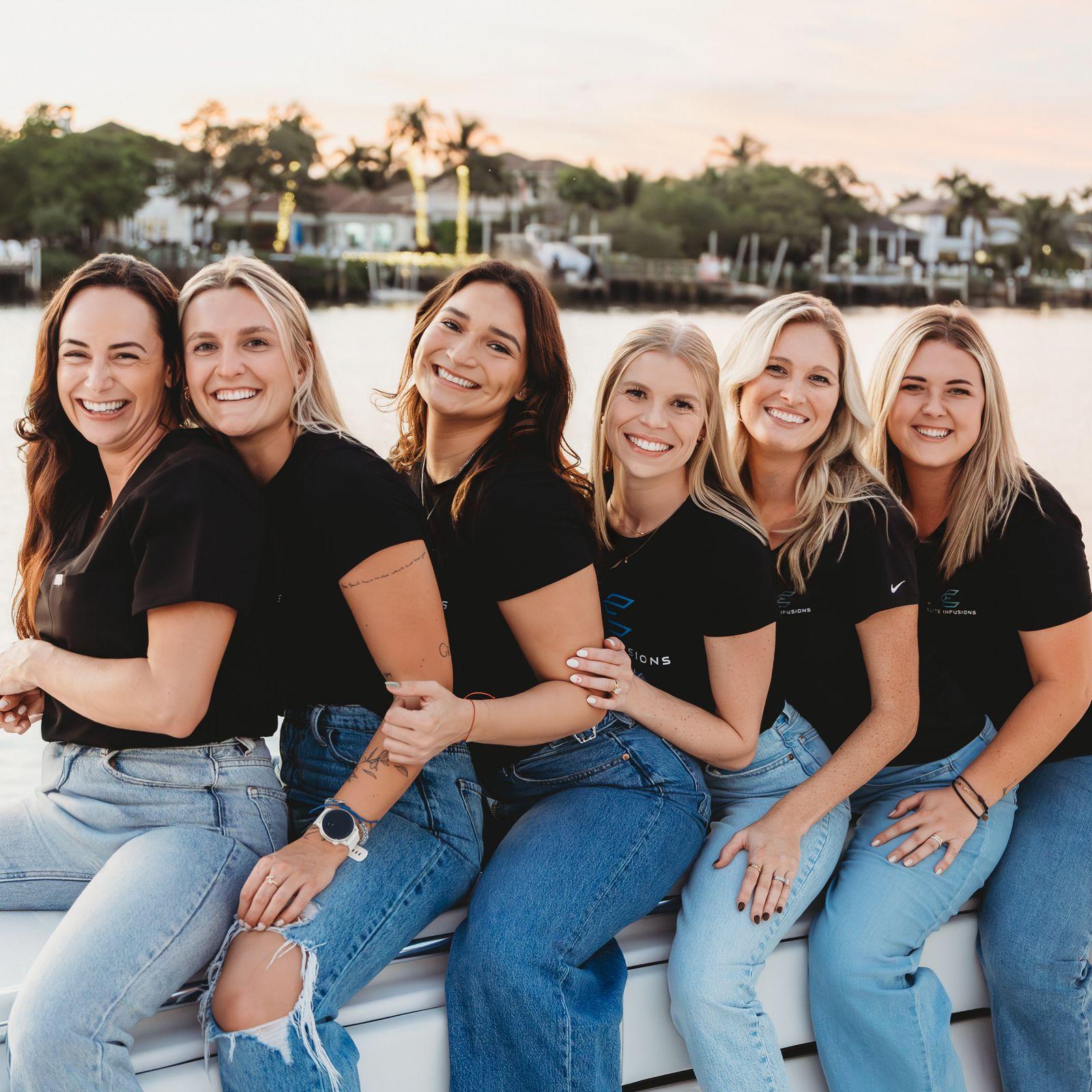 Six Elite Infusions nurses sitting together on a boat at sunset