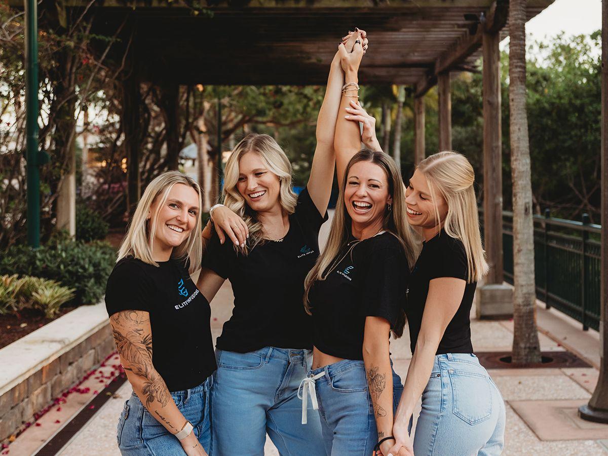 Four Elite team members laughing together under a pergola at golden hour