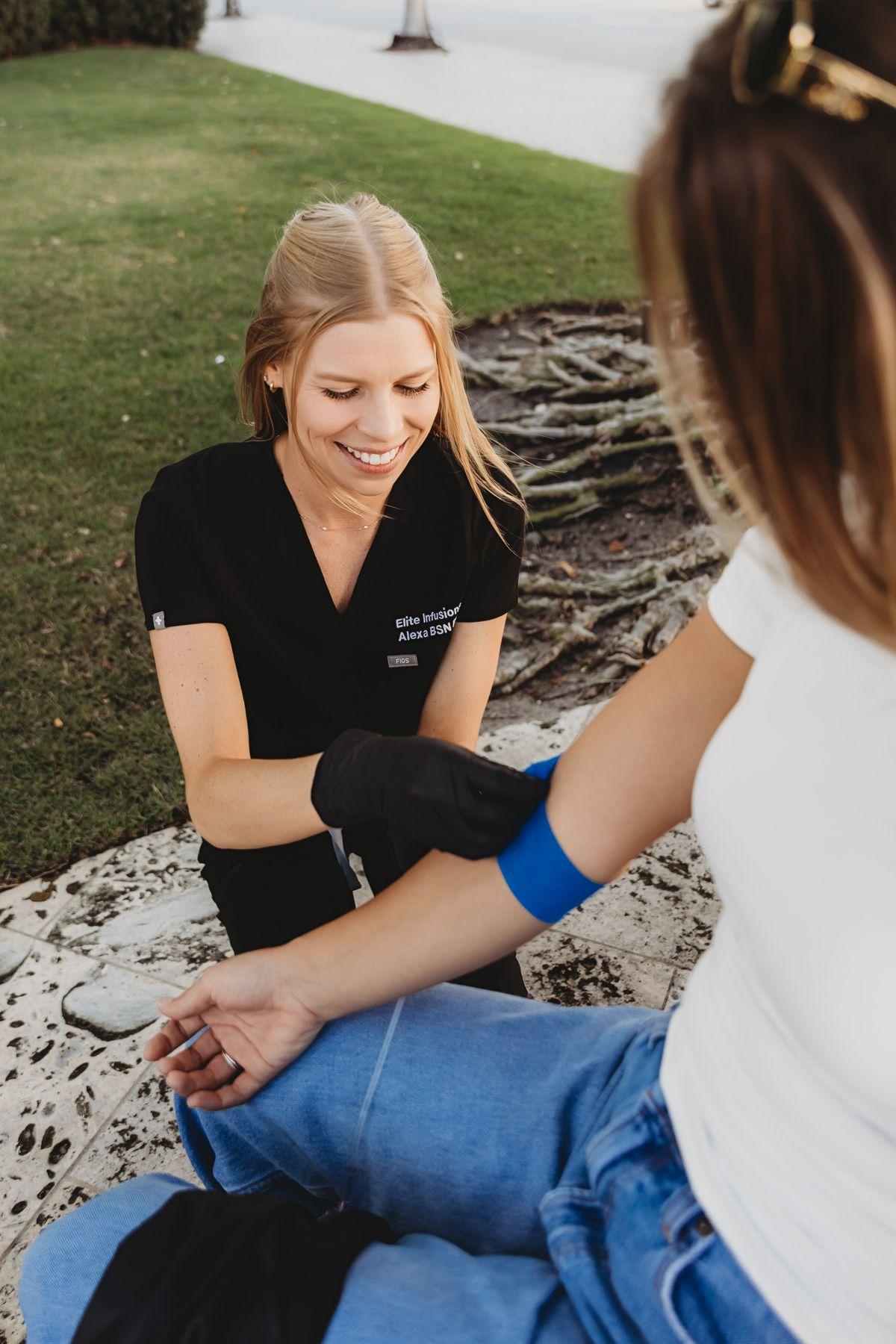 An Elite nurse placing an IV for a client seated outdoors